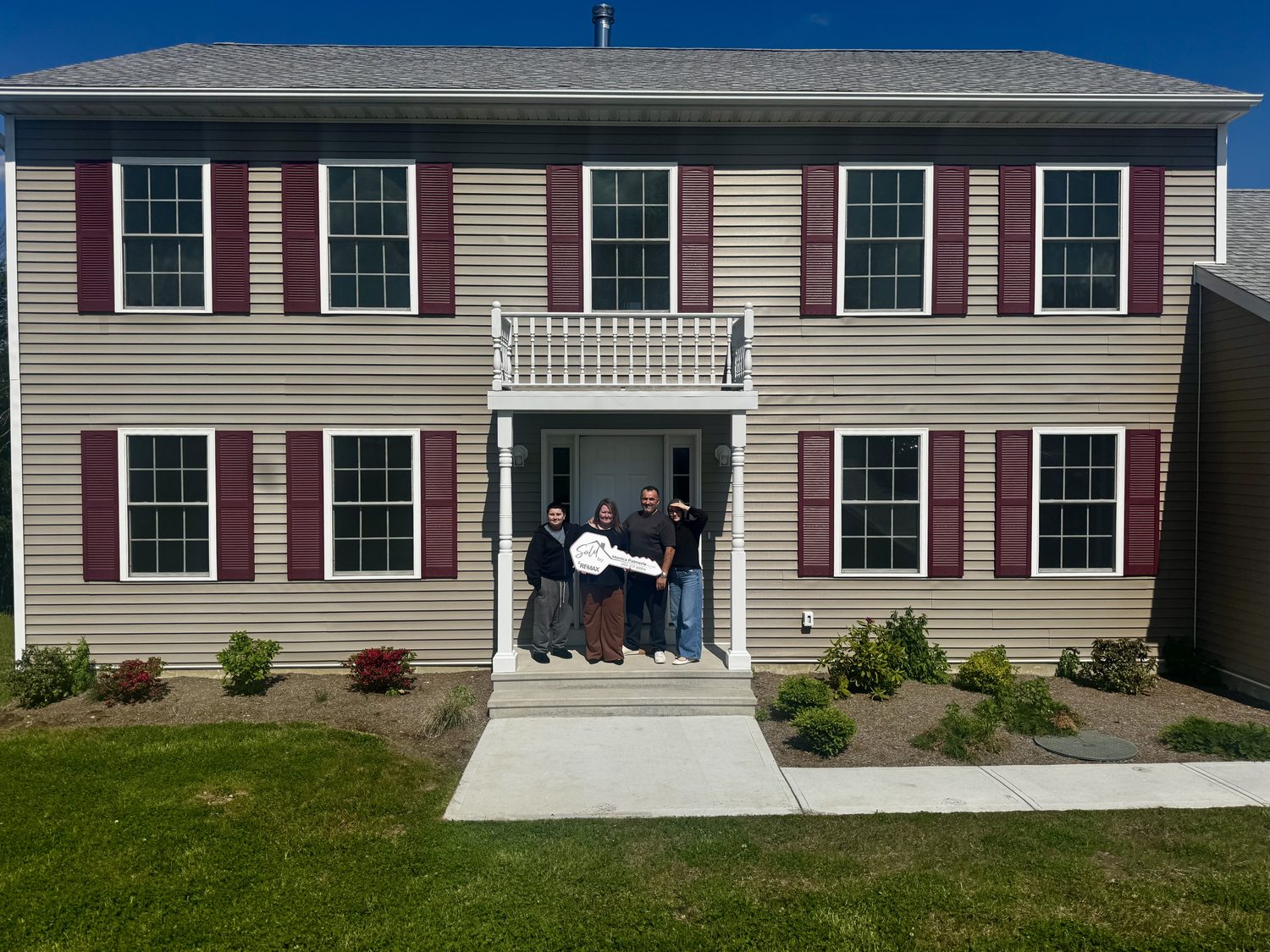Family holding a sold key in front of their new Connecticut home
